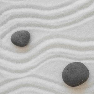 white sand with two smooth dark gray rocks and lines raked throughout