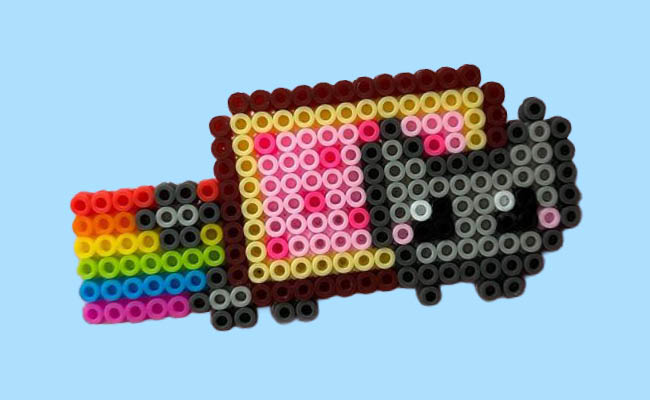 Pixel art of a cat with a Pop-Tart body and a trailing rainbow, made from colorful beads on a blue background.